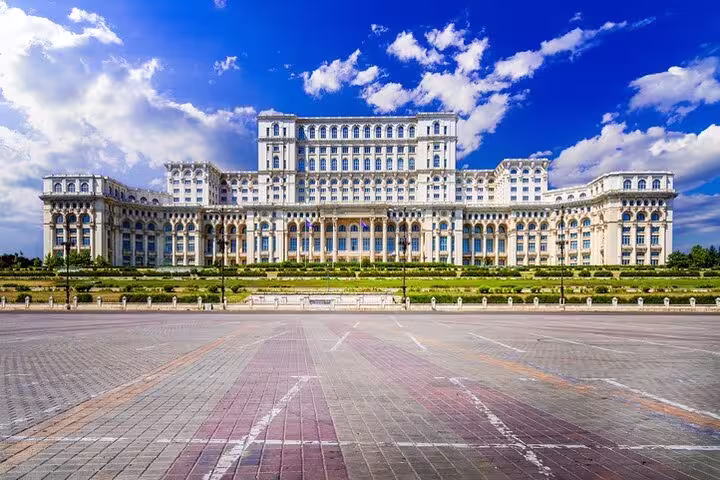 Wide-angle shot of the Palace of Parliament in Bucharest under a vibrant sky, showcasing its architectural grandeur for tourists.