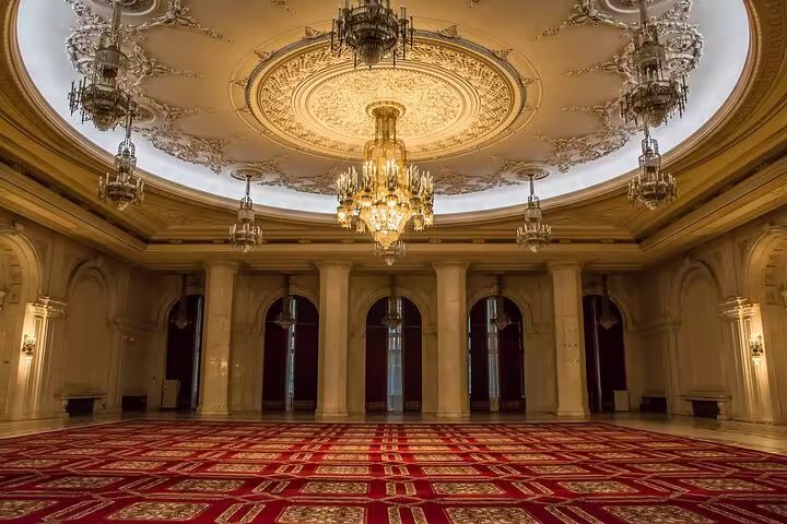 Luxurious chandelier and ornate ceiling in a grand hall of Bucharest's Palace of Parliament.