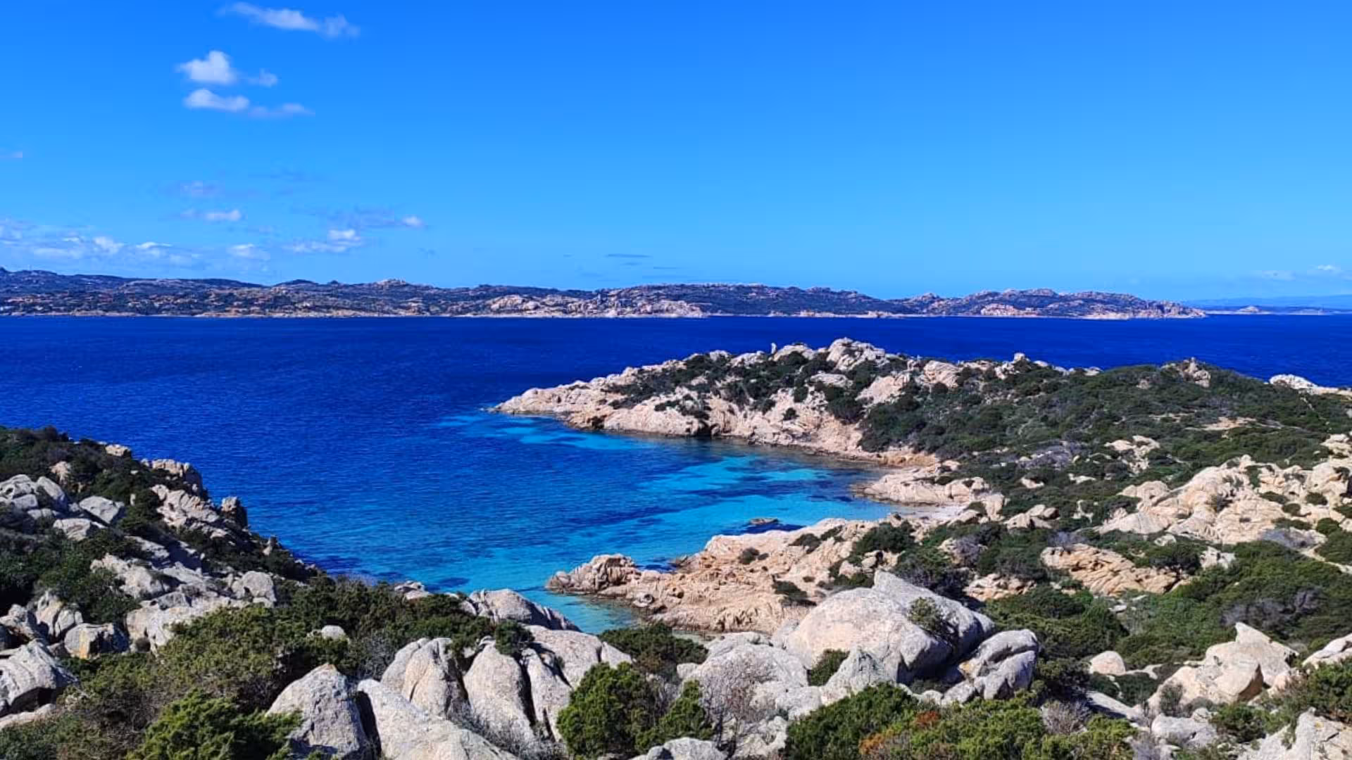 Crystal clear waters and rocky coastlines of La Maddalena from an e-bike tour departing Palau.