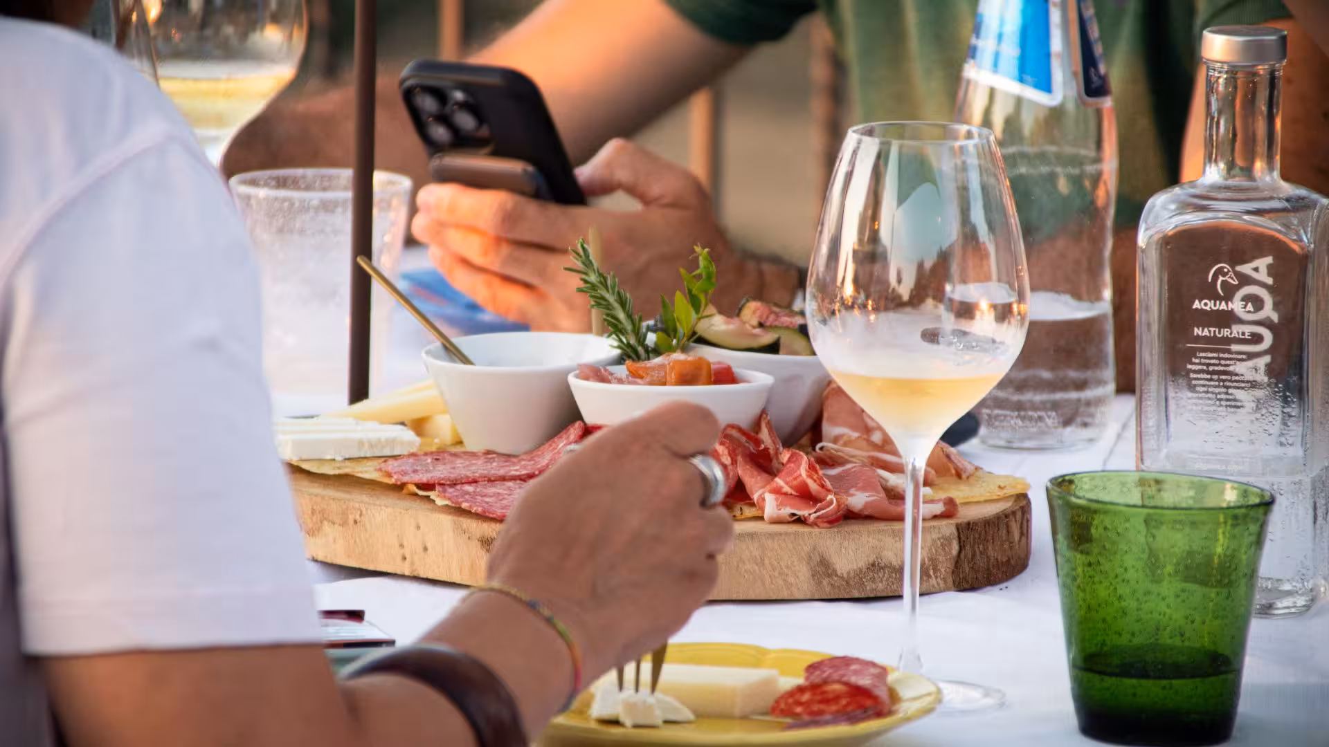 Guests indulging in charcuterie and wine at a Gallura winery in Palau, highlighting authentic culinary delights.