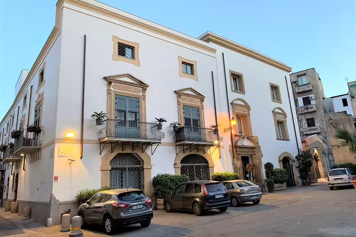 Elegant facade of Palazzo Brunaccini in Palermo, departure point for private airport transfer with modern cars parked outside