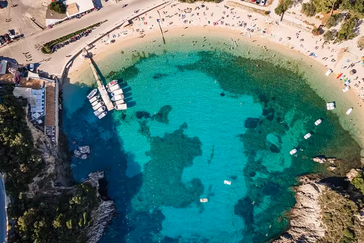 Aerial view of Paleokastritsa bay in Corfu with turquoise water, boats, and sandy beach stop