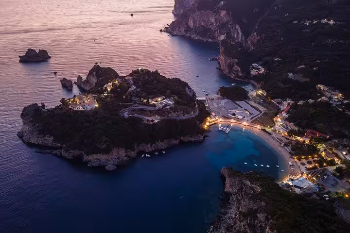 Aerial sunset view of Paleokastritsa bay, Corfu, on a private day tour with turquoise coves and cliffs