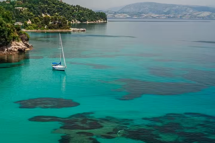 Sailboat on turquoise Paleokastritsa bay, Corfu, on a private tour with local tastings and scenic views