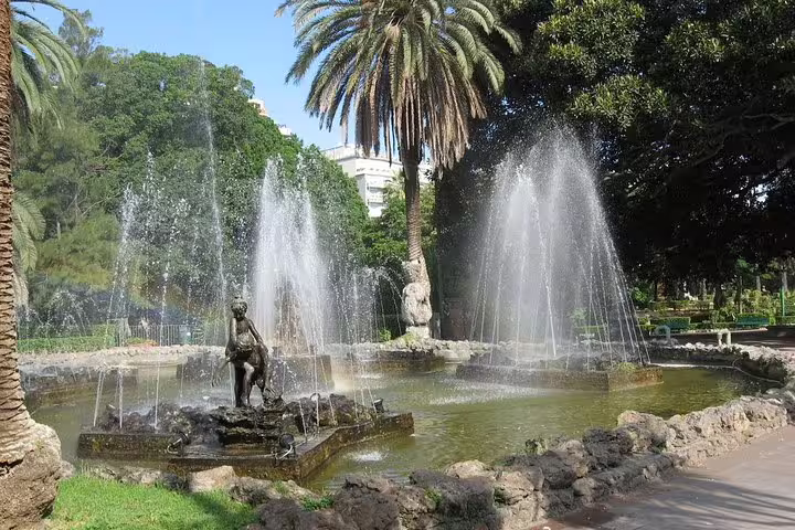 Elegant fountain and lush palm trees in Giardino Inglese park, Palermo, near hotels served by private airport transfer