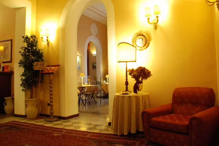 Elegant lounge of Hotel del Centro Palermo with warm lighting and classic décor, ideal arrival spot after PMO airport transfer