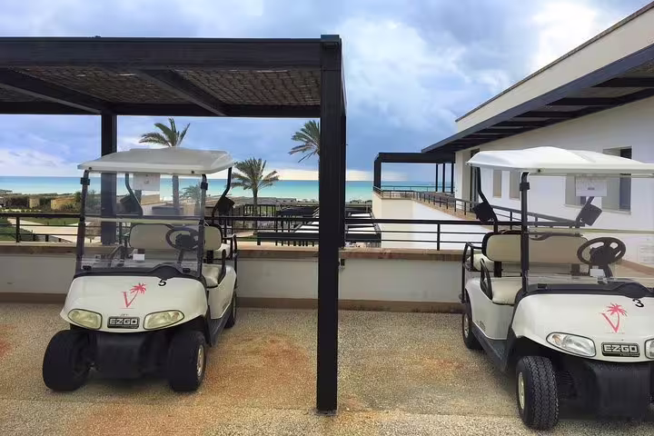 Golf carts parked at Verdura Resort with sea views, ideal arrival point after private transfer from Palermo airport