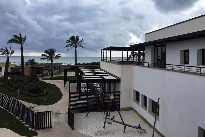 Modern seafront buildings and palm-lined paths at Verdura Resort Sciacca, destination of Palermo airport private transfer