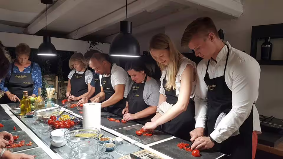 Hands-on Palermo cooking class with locals as guests chop tomatoes and prep Sicilian recipes in a home kitchen