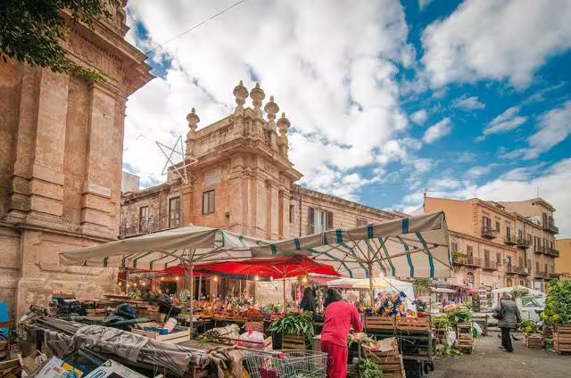 Colorful Palermo street market with fresh produce stalls set beneath historic baroque buildings on a private Sicily tour