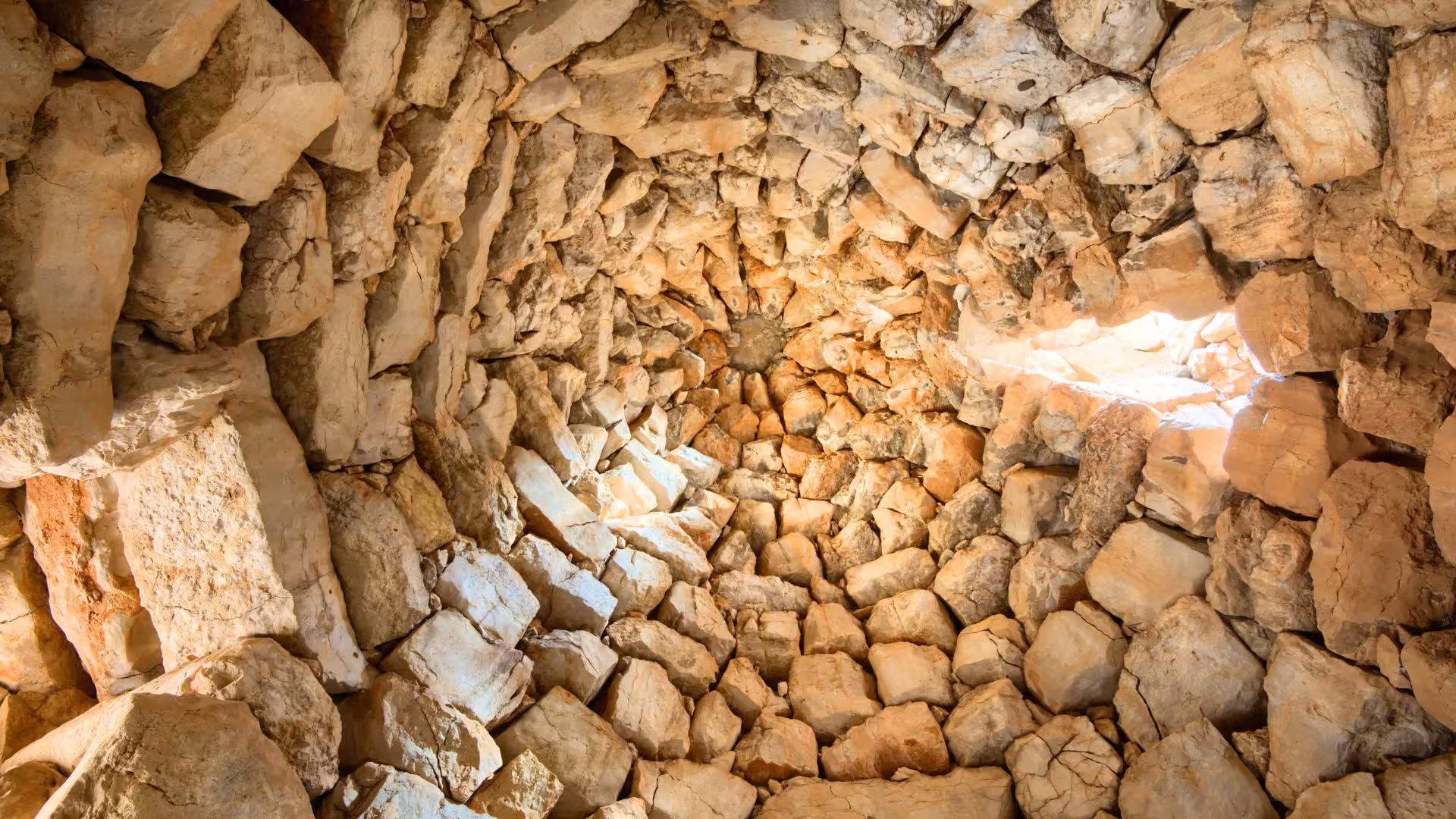 View from inside the Palmavera nuraghe, showcasing the intricate stonework and natural light in Alghero, Sardinia.