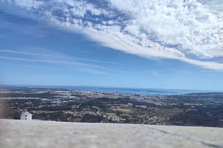 Breathtaking panoramic view from Palmela, capturing the vast landscape and coastline of Setúbal under a clear sky.
