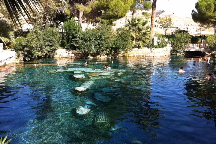 Swimmers in Cleopatra Antique Pool at Pamukkale, enjoying warm mineral water among ancient Roman ruins