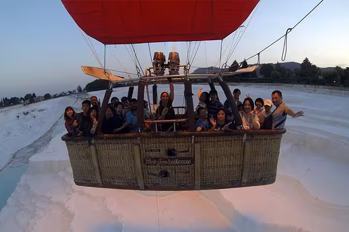 Passengers in basket on Pamukkale hot air balloon ride above travertine terraces during sunrise flight