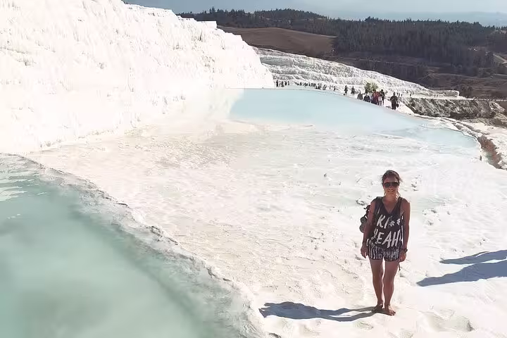 Traveler posing by turquoise thermal pools at Pamukkale travertines on a private full-day Antalya tour