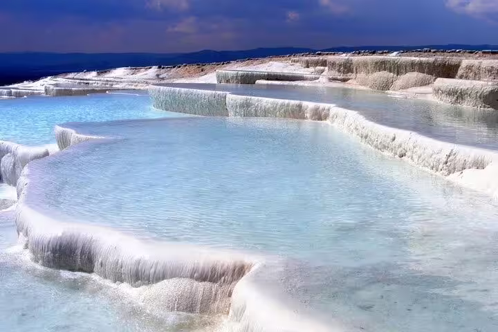 Stunning view of Pamukkale's natural thermal terraces with clear blue water, perfect for Ephesus and Pamukkale tours.