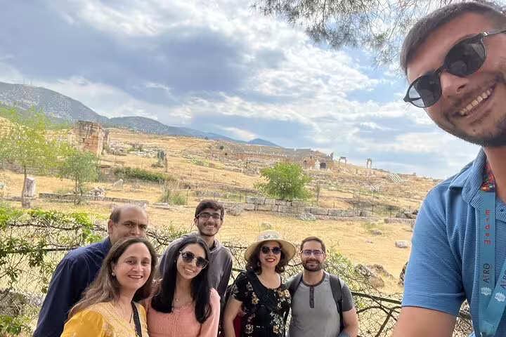 Group of tourists smiling in front of ancient ruins during Pamukkale day tour from Istanbul with guided experience.