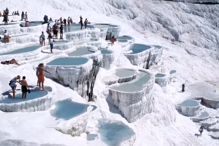 Visitors wade in Pamukkale travertine pools on a private tour from Denizli Airport, Turkey