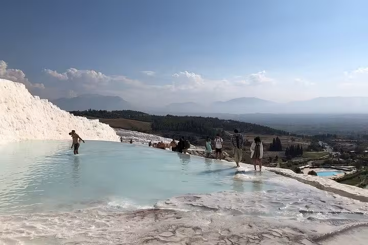 Travelers wade in Pamukkale travertine pools on a private full-day tour from Antalya with panoramic views