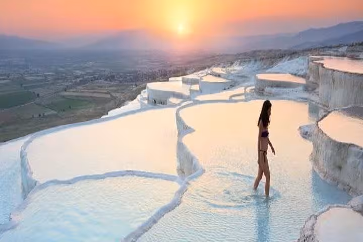 Traveler walking in Pamukkale travertine pools at sunset on a private full-day Pamukkale tour from Antalya