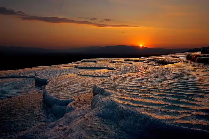 Sunset over Pamukkale's travertine terraces, highlighting the natural beauty on an Istanbul day tour with flight.