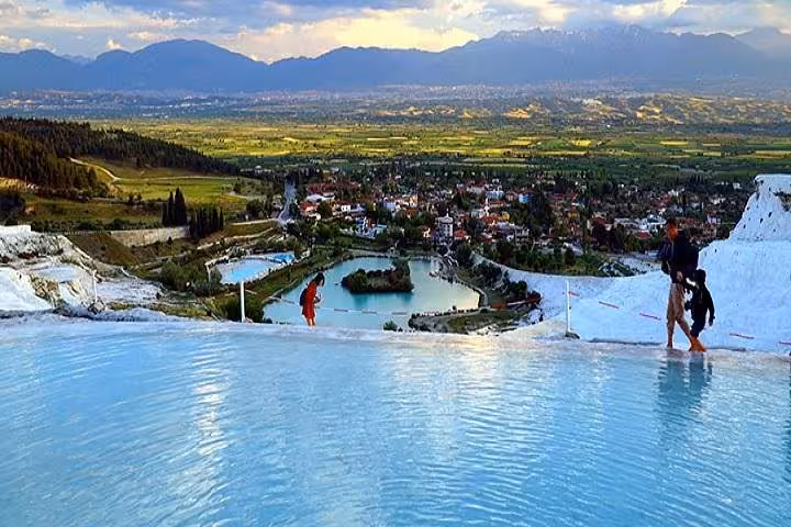 Pamukkale travertine terraces with infinity pool view over Denizli valley at sunset on guided Pamukkale tour
