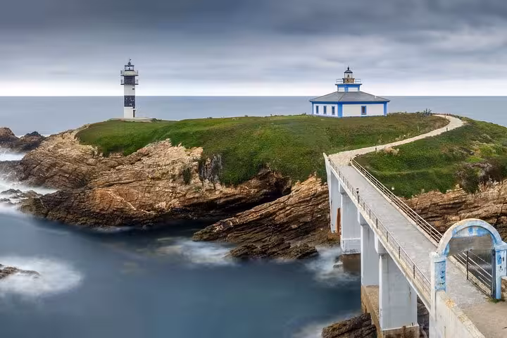 Pancha Island's scenic lighthouse and rugged cliffs with a connecting bridge over the Atlantic Ocean, Asturias.