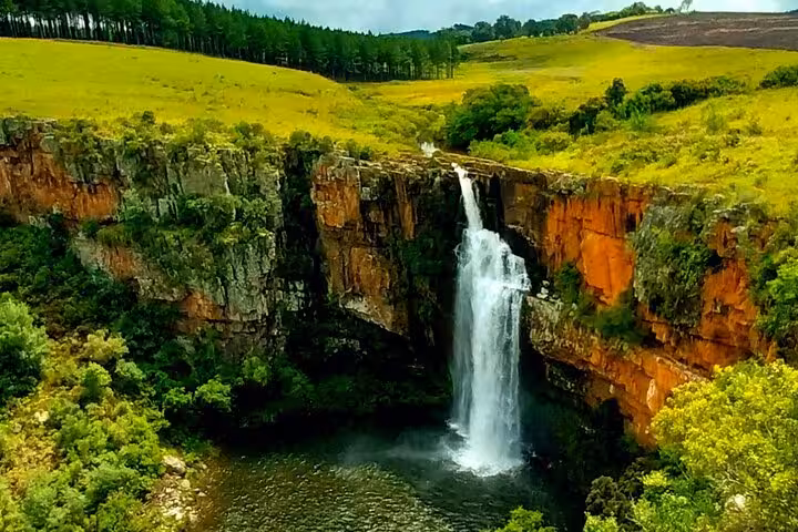 Majestic waterfall cascading down a rocky cliff surrounded by lush greenery on the Panorama Guided Experience tour.