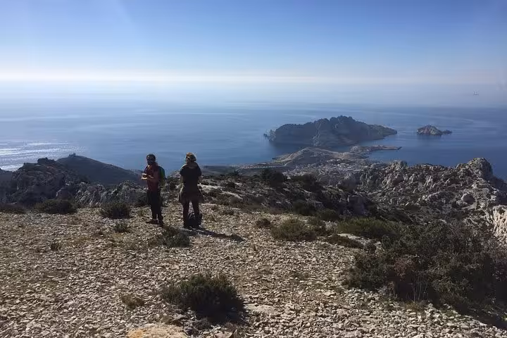 Guided hikers on rocky ridge above Marseille and Les Calanques, panoramic coastal hike with island views