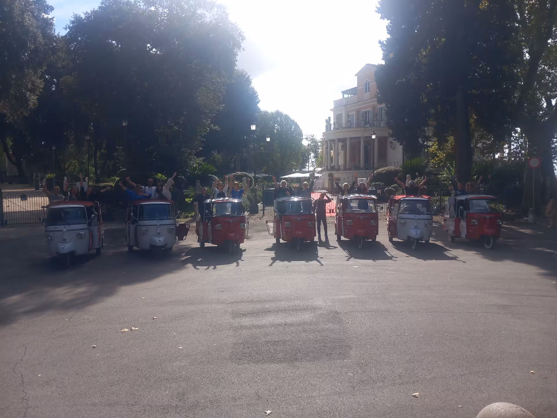Tourists in vibrant tuk-tuks lined up in front of a historic villa during the Pantheon Combo Tour.