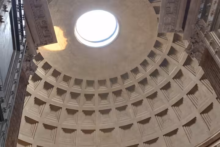 Interior view of the Pantheon dome with sunlight filtering through the oculus, showcasing architectural grandeur.