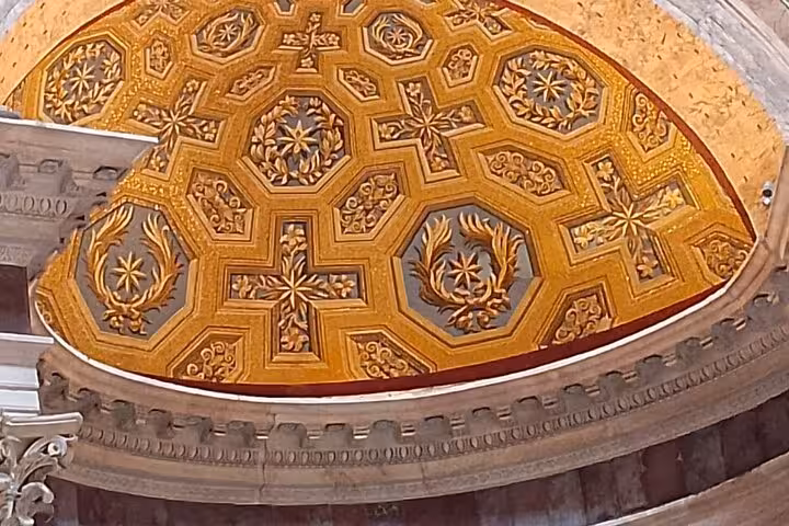 Close-up of the ornate golden interior dome of the Pantheon in Rome, showcasing detailed geometric patterns.