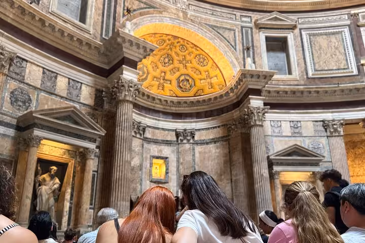 Tourists admire the detailed interior of the Pantheon, featuring stunning Roman architecture and sculptures.