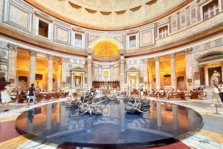 Interior view of the Pantheon in Rome with tourists exploring its grand architecture and historical artworks.