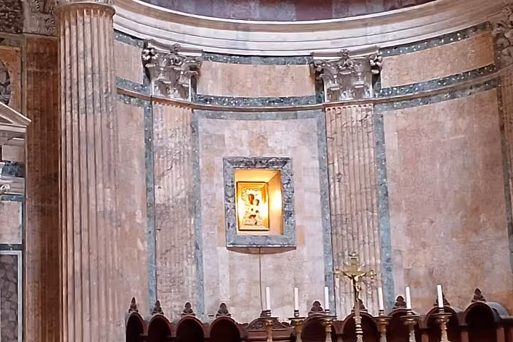 Close-up of the Pantheon's ornate interior wall featuring classical columns and a lit religious icon, available with a digital audio guide.
