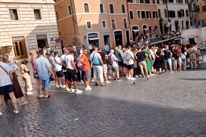 Tourists gather outside the Pantheon in Rome, awaiting entry with tickets and audio guides for a historical tour.