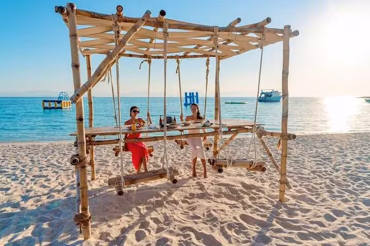 Guests relaxing on bamboo swing at Paradise Island beach during Hurghada VIP boat trip and snorkeling day tour
