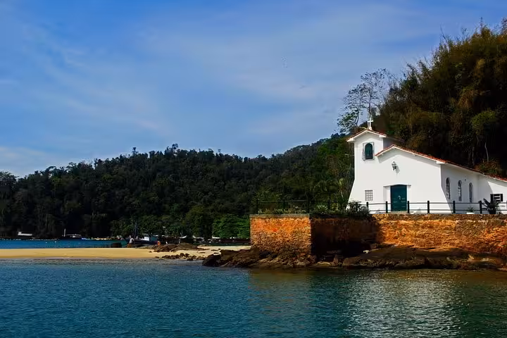 Charming white chapel perched on rocky coastline of Paradise Island seen from the speedboat tour.