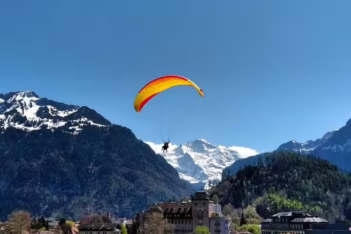 Paraglider soaring above Grindelwald with stunning snow-capped mountains in the background.