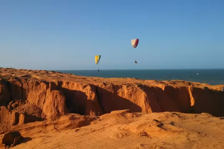 Paragliders over dramatic red cliffs by the ocean, highlight viewpoint on a 3 beaches in 1 day coastal tour