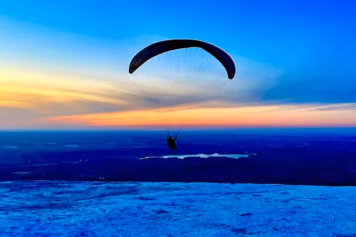 Paraglider gliding at dusk over the Agafay Desert, capturing the serene beauty of Marrakech's unique adventure landscape.