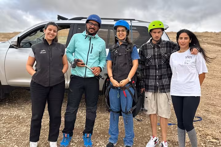 Group of paragliding enthusiasts preparing for Agafay Desert adventure near Marrakech with safety gear and vehicle.