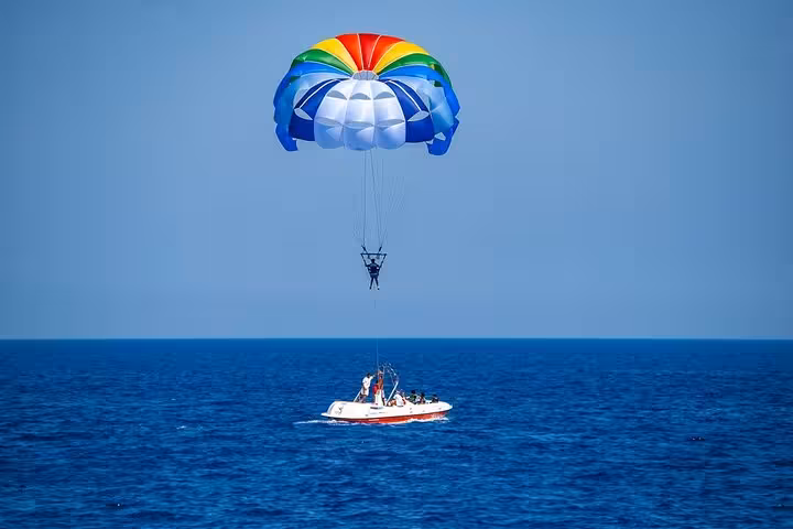 Parasailing over the Red Sea in Hurghada with a rainbow parachute above a speedboat, private transfer tour