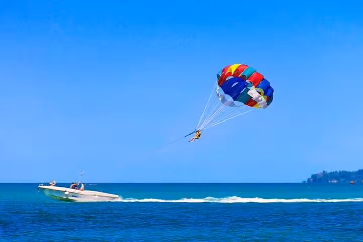 Parasailing over the Red Sea in Hurghada, colorful canopy behind speedboat with private transfer tour