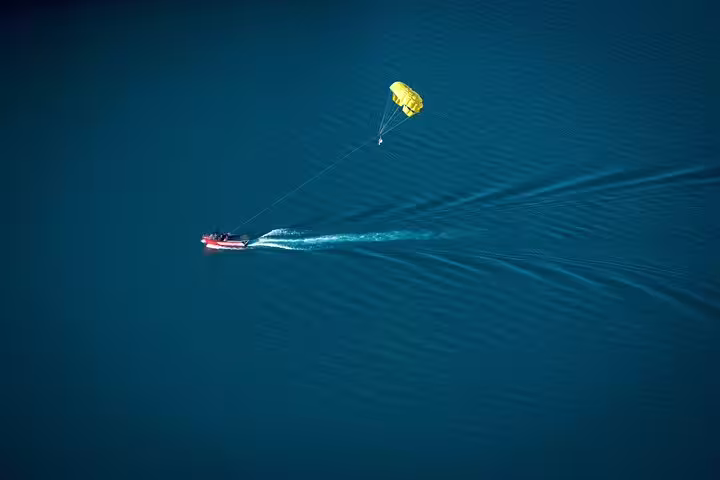 Aerial view of Sharm El Sheikh parasailing tour, speedboat towing yellow parachute across the Red Sea