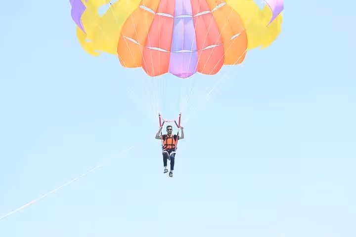 Solo parasailer under bright canopy in Sharm El Sheikh over the Red Sea, parasailing tour with private transfer