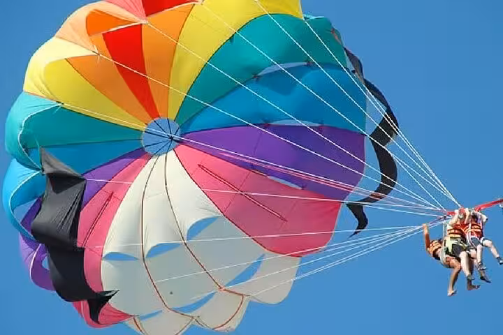 Colorful parasail canopy lifting two riders above Sharm El Sheikh coastline on Red Sea parasailing tour