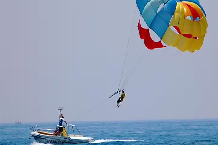 Parasailing boat tow in Sharm El Sheikh, rider lifting off over the Red Sea with bright parachute canopy