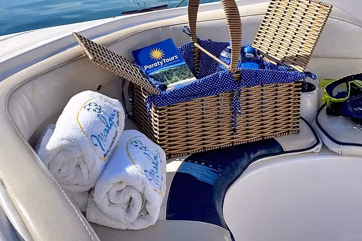 Picnic basket with towels and a tour guide on a cushioned seat, ideal for a comfortable Paraty boat tour experience.
