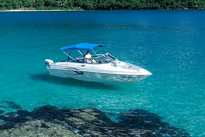 Sleek white boat cruising in Paraty's crystal-clear turquoise waters, perfect for an exclusive boat tour.